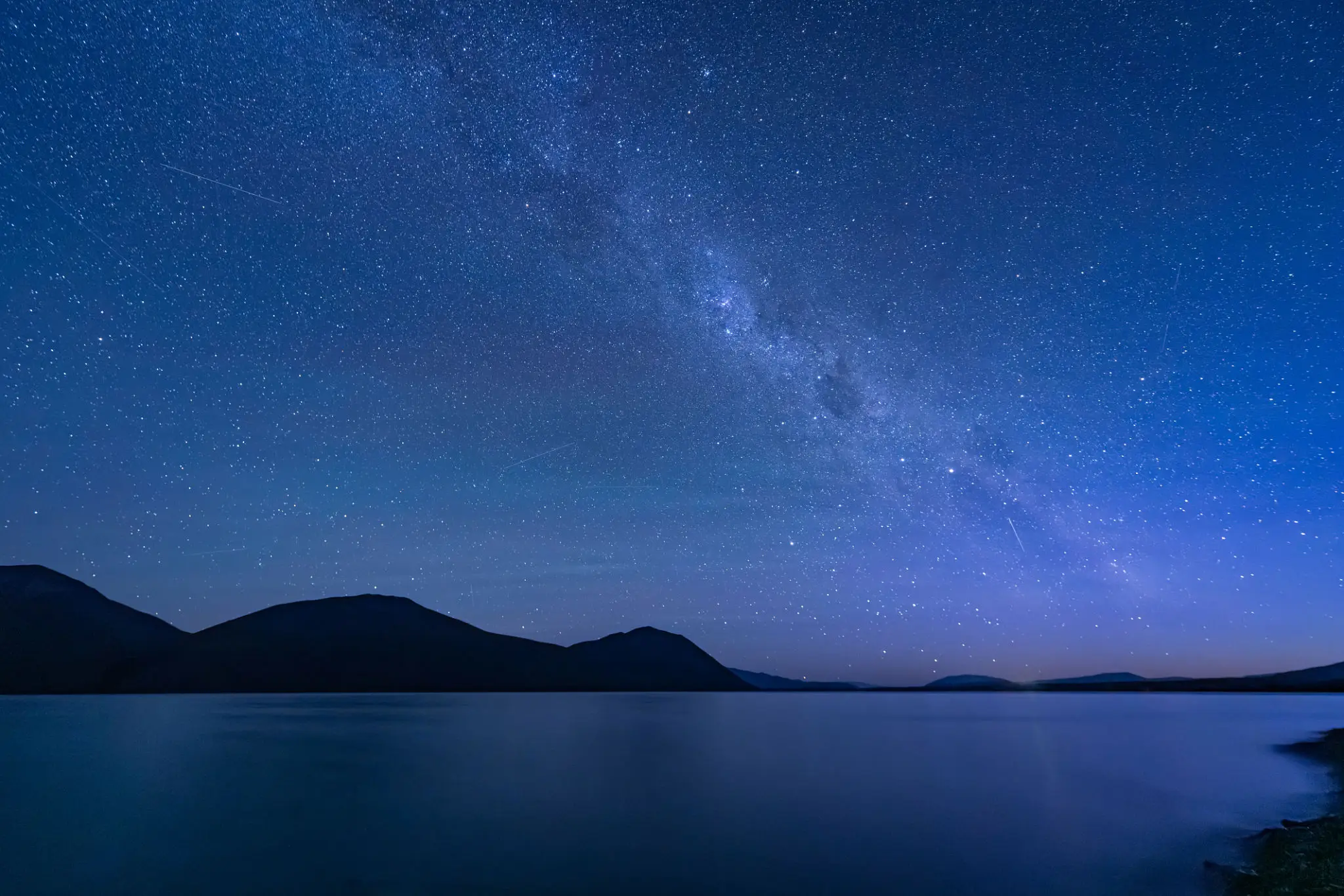Milky Way over tranquil lake and mountains